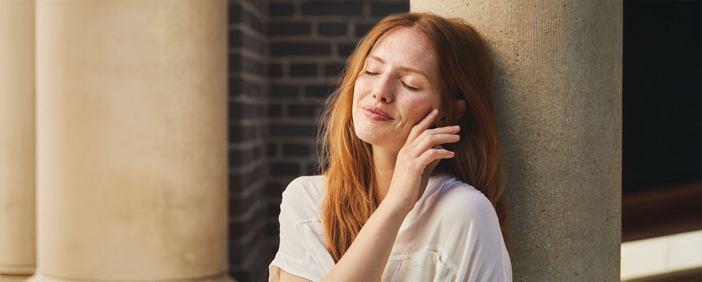 Femme assise, adoss&eacute;e &agrave; une colonne de pierre, regardant le soleil.
